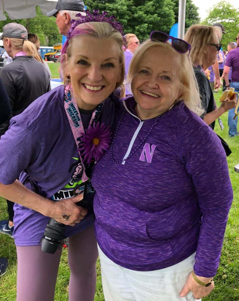 two women smiling wearing violet top