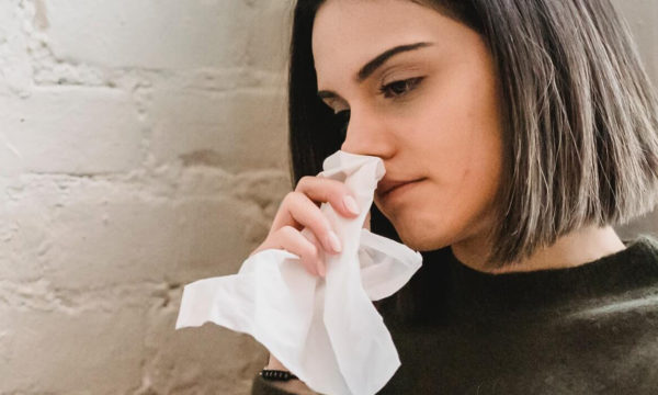 woman holding tissue to her nose