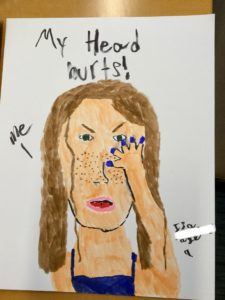 A drawing of a person with brown hair and freckles holding their head, captioned 
