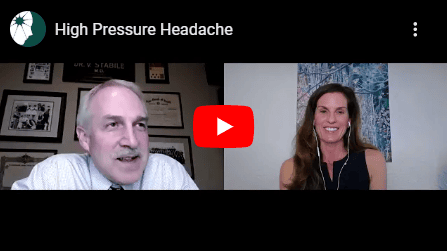 Screenshot of a paused YouTube video titled "High Pressure Headache," showing a man in a shirt and tie on the left and a smiling woman on the right in a split-screen view.