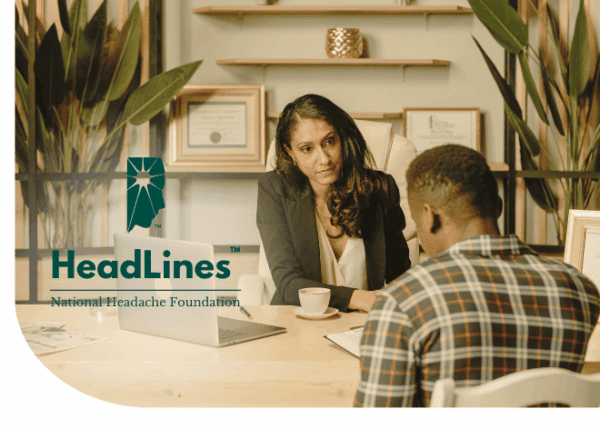 A woman in business attire talks to a man across a desk in an office, with the 