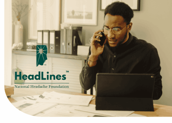 A man speaks on the phone while working at a desk with papers and a tablet. The National Headache Foundation HeadLines logo is visible on the left side.