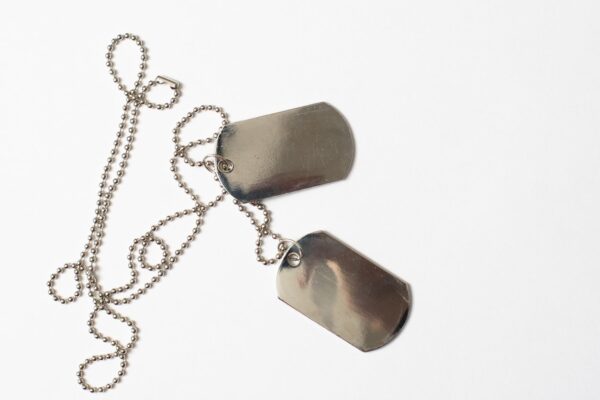 A pair of blank metal military dog tags on a beaded chain, displayed on a white background.