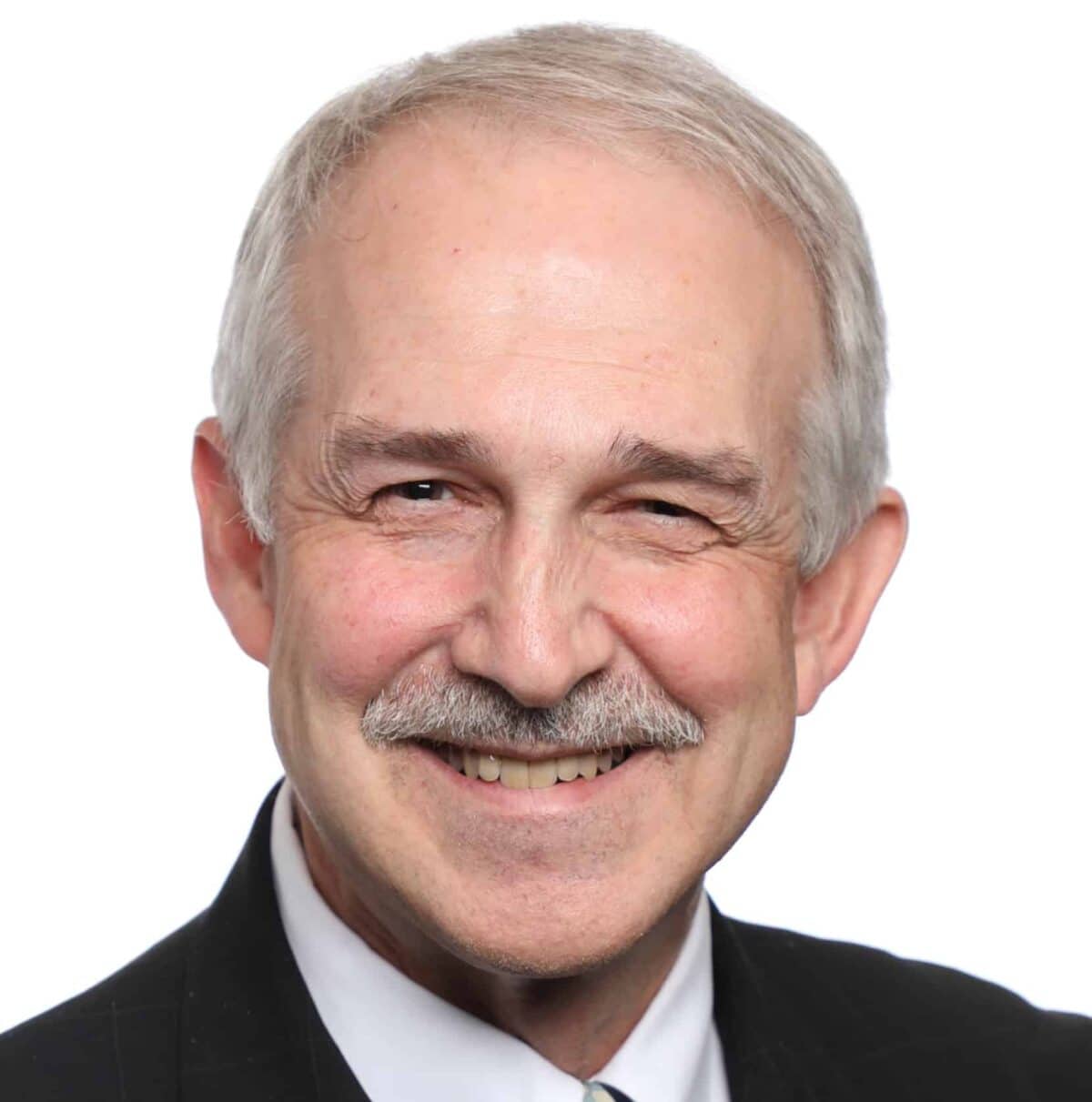 A middle-aged man with gray hair, a mustache, and a suit smiles at the camera against a plain white background.